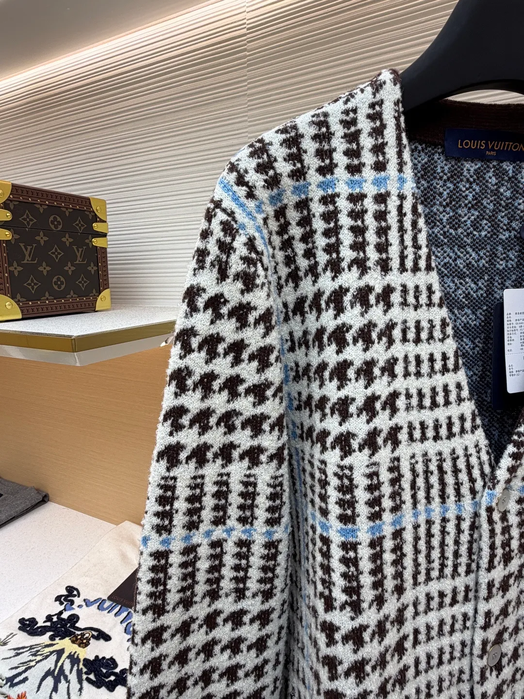 LOUIS VUITTON letter intarsia houndstooth knitted jacquard cardigan ●Original version: purchased and developed by 14743 ●Item number: 1681873-C00 ●Fabric: wool blended fabric ●Technology: jacquard knitting ●Color: black, white and blue ●Version: fitted version ●Weight: about 695 grams ●Size: S-M-L-XL ●Description: The main pattern of this cardigan is woven with full-width jacquard technology, using 69% sheep wool blended with 31% nylon yarn to interweave the houndstooth pattern with light blue line texture. At the same time, the brand logo elements are integrated into the body through intarsia technology, and the edges of the pattern are connected delicately and seamlessly. The collar, cuffs and hem are made of 100% sheep wool ribbed fabric, and are edged with double-needle seaming technology, which has both elasticity and shaping effect. The front placket is equipped with natural-textured buttons, and the side seam pockets use invisible stitching technology to blend naturally with the jacquard texture of the body. The overall shape is shaped through three-dimensional tailoring, and the shoulders are stitched with seamless stitching to ensure fit and comfort. The entire piece is finished with handcrafted details in an Italian workshop, showing the craftsmanship precision of high-quality knitted items. The overall wiring is straight and delicate, the fabric is comfortable and soft, and the color is consistent without color difference. It can be matched with the same style to create a fashionable look and control various occasions. Customized accessories, complete with three standards, same style for men and women!